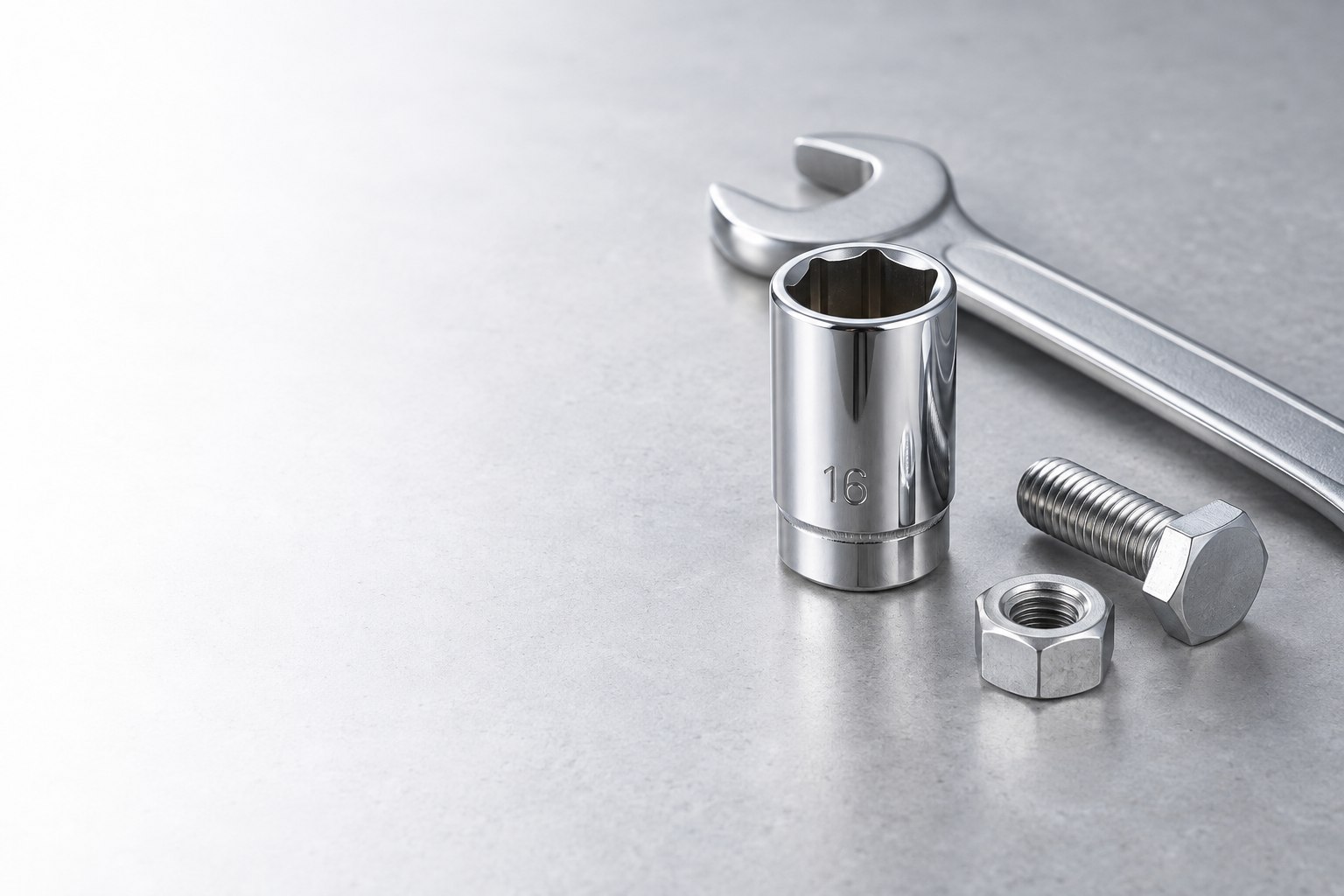 Chrome socket, wrench, bolt and nut on a light workbench